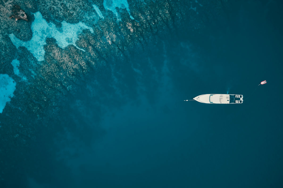 Boat in turquoise water from above, Bay Islands